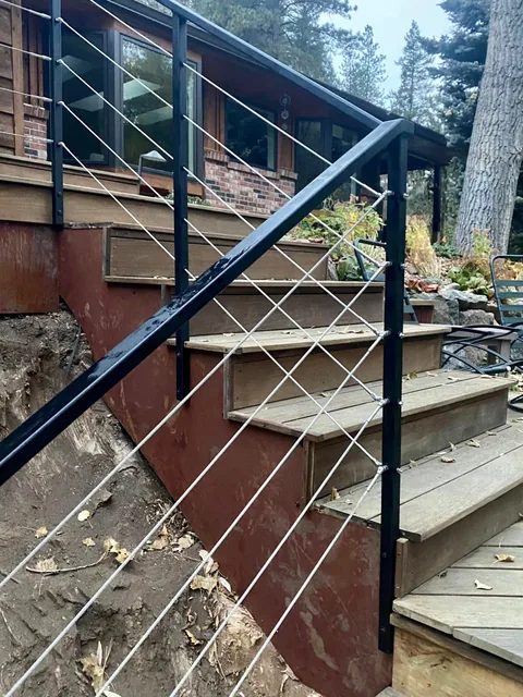Black exterior stair railing with stainless cable infill