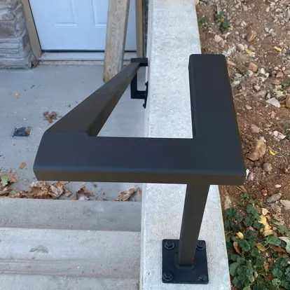 Black steel handrail mounted beside concrete steps