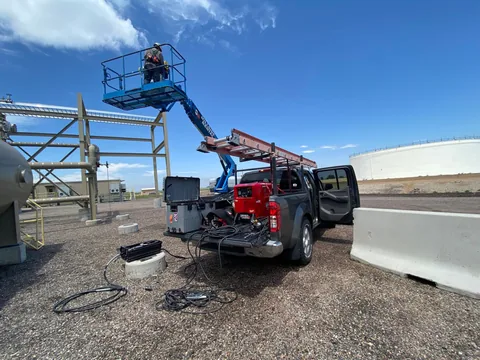 Mobile welding setup beside an elevated industrial work area