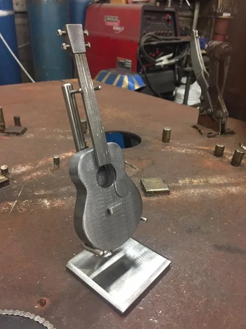 Small steel guitar sculpture on a metal base