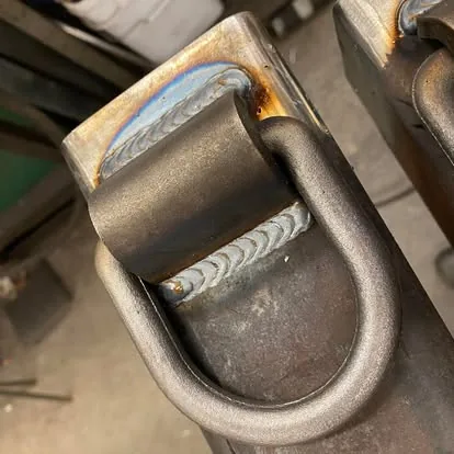 Close view of clean welds joining a steel loop and plate