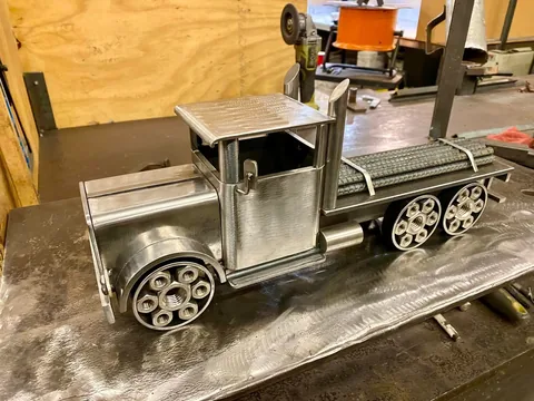 Hand-fabricated steel model truck on a welding table